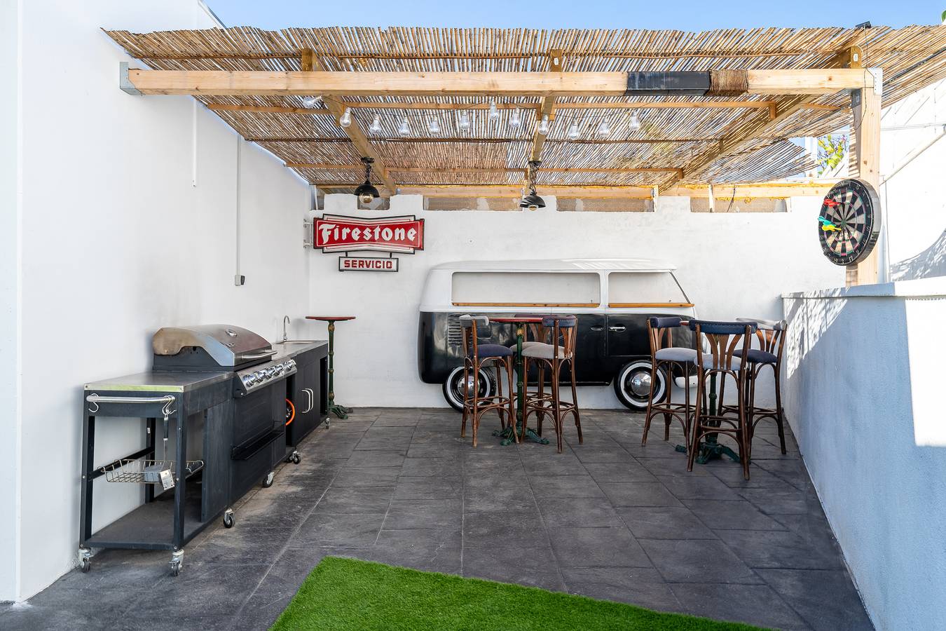 Zona de barbacoa con comedor exterior bajo pérgola