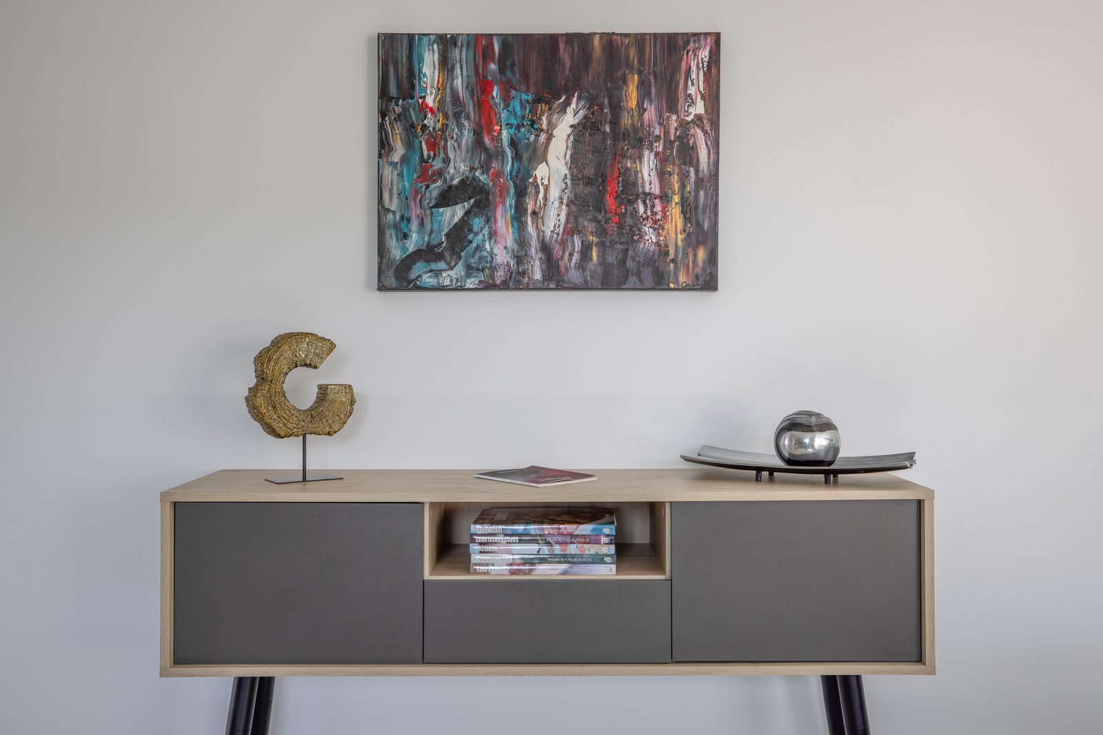 Decoración interior con mueble de diseño, cuadro abstracto y objetos decorativos en La Villa del Roc, Roda de Berà